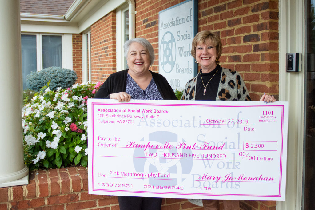photograph of Pamper Me Pink representative and Mary Jo Monahan holding a large check