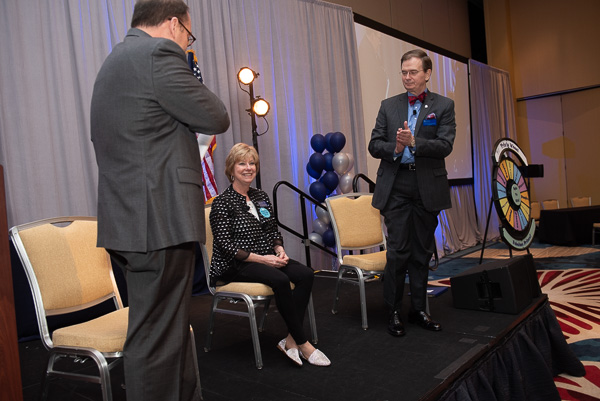 photograph of Tim Brown and Harold Dean applauding Mary Jo Monahan on stage.