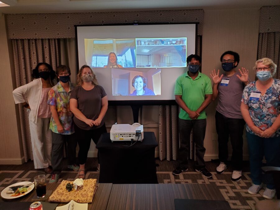 Photograph of committee members with virtual attendees on a screen