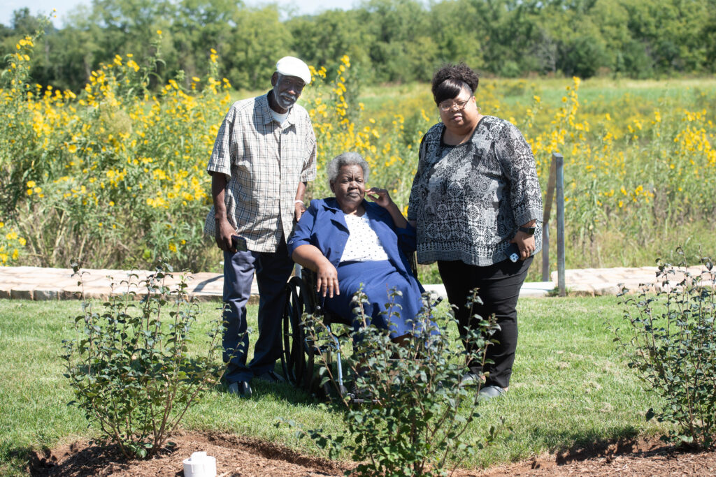 Photo of a man and two women in a rustic garden on a sunny day