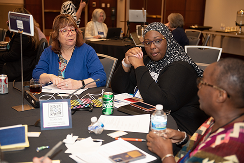 Photo of three women having a conversation around a conference table.