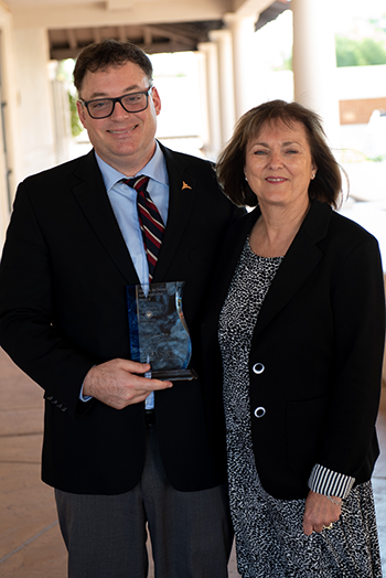 Photograph of a man holding a plaque and a woman, both smiling.