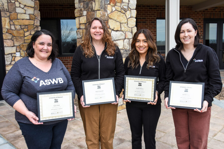 Photograph of four ASWB staff members smiling and displaying their certificates for the ADA certification program they completed.